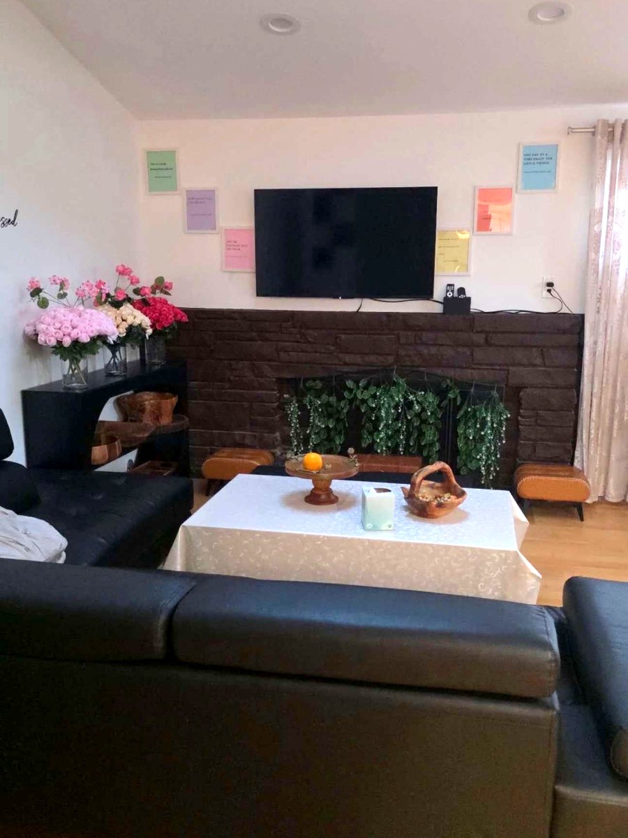 The living room at Blessed Home Senior Care, with sofas, a fireplace and fresh flowers